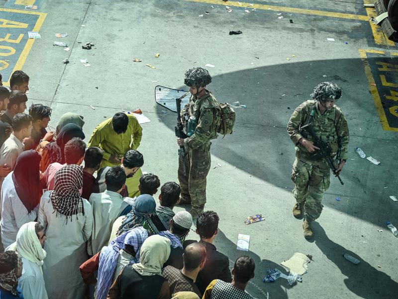 U.S. soldiers stand guard as Afghans wait Monday at the Kabul airport following the swift end to Afghanistan's 20-year war. U.S. soldiers stand guard as Afghans wait Monday at the Kabul airport following the swift end to Afghanistan's 20-year war.