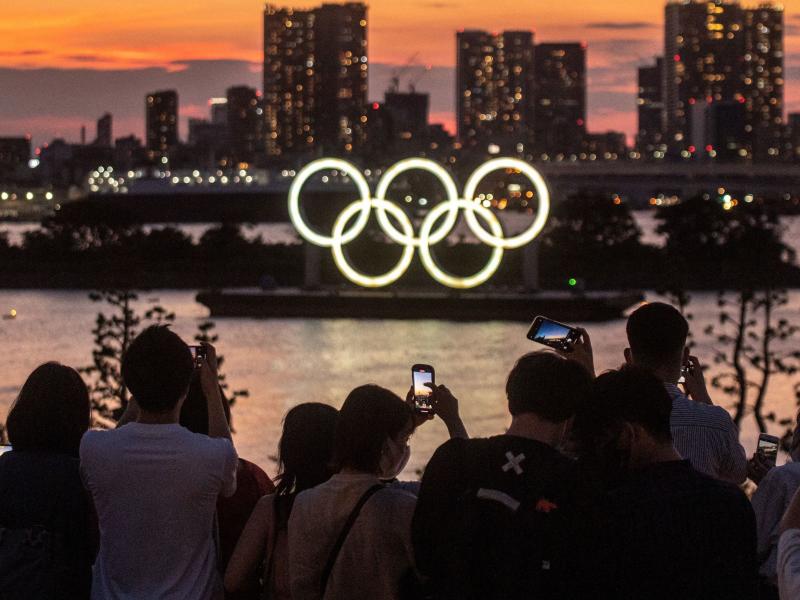 People take pictures as the Olympic rings lit up at dusk on the Odaiba waterfront in Tokyo on Thursday, the eve of the official start of the Tokyo 2020 Olympic Games. People take pictures as the Olympic rings lit up at dusk on the Odaiba waterfront in Tokyo on Thursday, the eve of the official start of the Tokyo 2020 Olympic Games.