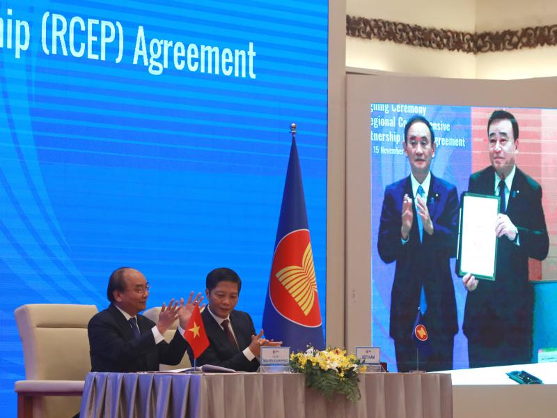 Vietnamese Prime Minister Nguyen Xuan Phuc (left) and Trade Minister Tran Tuan Anh applaud next to a screen showing Japanese Prime Minister Yoshihide Suga and Trade Minister Hiroshi Kajiyama holding up signed RCEP agreement, in Hanoi, Vietnam. China and 1 Vietnamese Prime Minister Nguyen Xuan Phuc (left) and Trade Minister Tran Tuan Anh applaud next to a screen showing Japanese Prime Minister Yoshihide Suga and Trade Minister Hiroshi Kajiyama holding up signed RCEP agreement, in Hanoi, Vietnam. China and 1