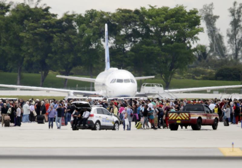 People stand on the tarmac at the Fort Lauderdale-Hollywood International Airport in Florida on Friday after a shooter opened fire inside a terminal, killing at least five people and wounding eight others before being taken into custody. People stand on the tarmac at the Fort Lauderdale-Hollywood International Airport in Florida on Friday after a shooter opened fire inside a terminal, killing at least five people and wounding eight others before being taken into custody.
