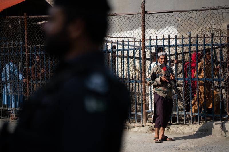 A Taliban guard stands on the Afghan side of the Torkham border crossing with Pakistan. People behind wait either to leave Afghanistan or to receive those returning to the country. A Taliban guard stands on the Afghan side of the Torkham border crossing with Pakistan. People behind wait either to leave Afghanistan or to receive those returning to the country.