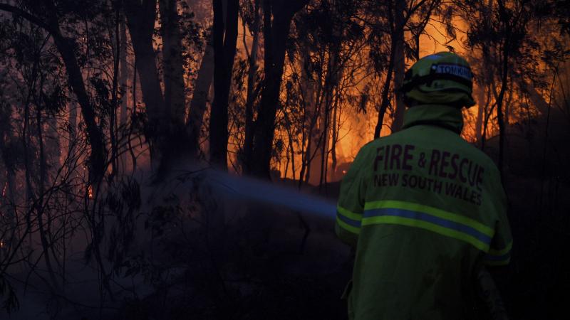 A firefighter battles a wall of flames Friday in Woodford, New South Wales. A firefighter battles a wall of flames Friday in Woodford, New South Wales.