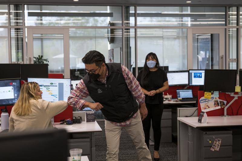 Employees elbow bump at a JLL office in Menlo Park, Calif., in September. With the delta variant surging, mask mandates are returning, and some employers are now requiring employees to be vaccinated before coming to the office. Employees elbow bump at a JLL office in Menlo Park, Calif., in September. With the delta variant surging, mask mandates are returning, and some employers are now requiring employees to be vaccinated before coming to the office.