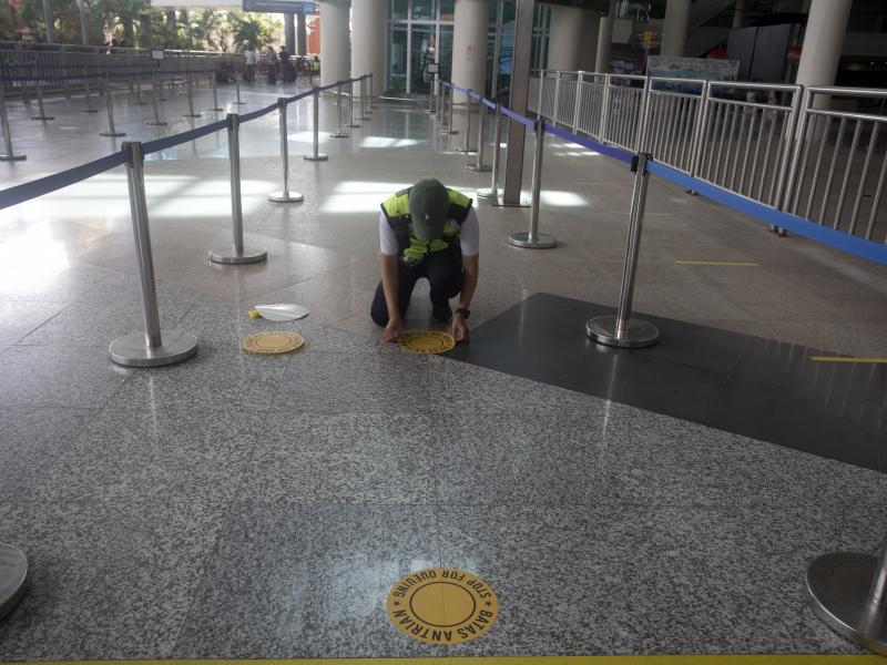 An airport worker marks queue line for the reopening of International Ngurah Rai Airport in Bali, Indonesia, Thursday. An airport worker marks queue line for the reopening of International Ngurah Rai Airport in Bali, Indonesia, Thursday.