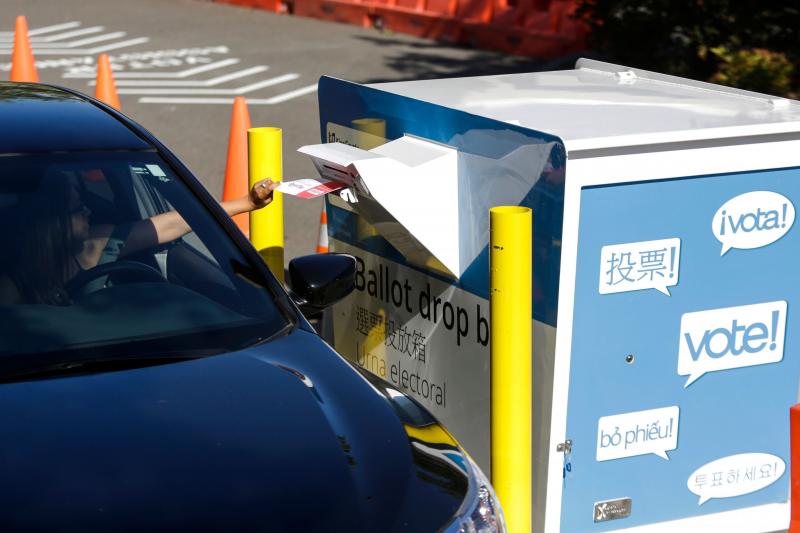A voter inserts a ballot in a drive-up drop box last week in Renton, Wash., in that state's primary. With more states expanding absentee voting due to the pandemic, the use of drop boxes is growing and leading to legal challenges from some Republicans. A voter inserts a ballot in a drive-up drop box last week in Renton, Wash., in that state's primary. With more states expanding absentee voting due to the pandemic, the use of drop boxes is growing and leading to legal challenges from some Republicans.