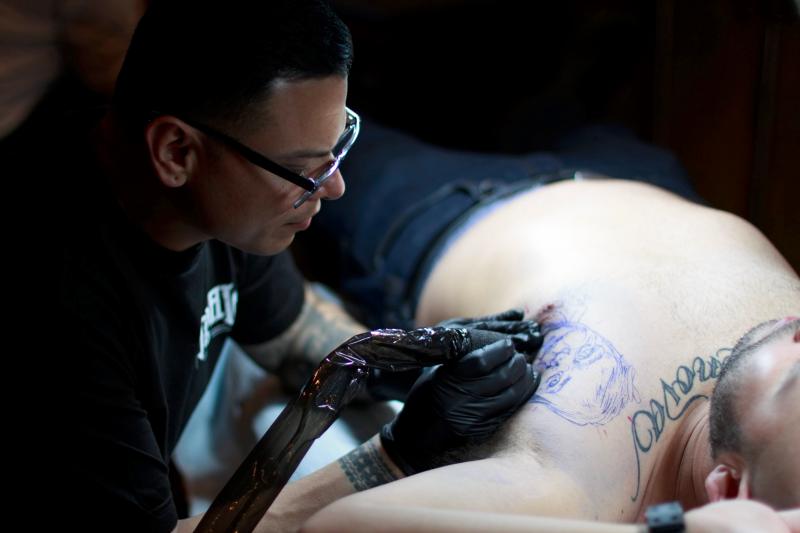 Chuey Quintanar tattooing a portrait of his client's first born daughter. Chuey Quintanar tattooing a portrait of his client's first born daughter.