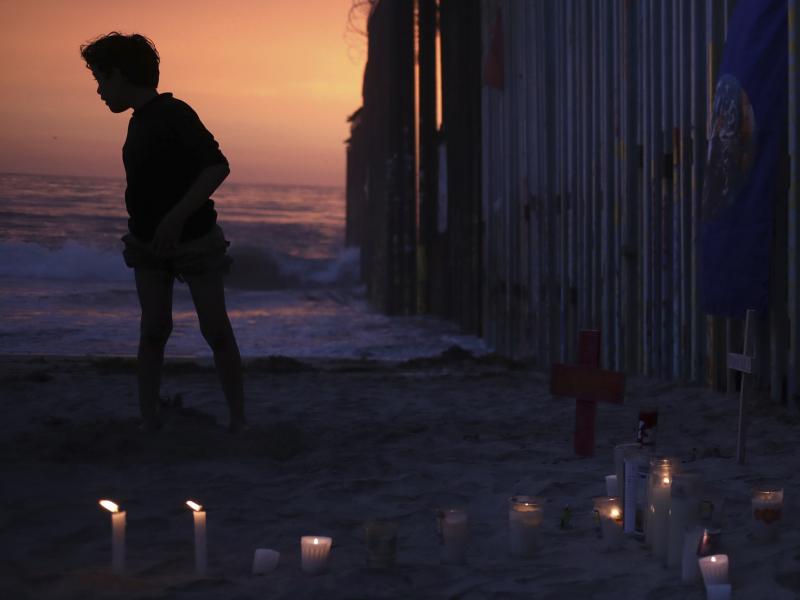 A youth stands Sunday by the border fence that separates Mexico from the U.S., where candles and crosses stand in memory of the father and daughter who died during their journey toward the U.S. A youth stands Sunday by the border fence that separates Mexico from the U.S., where candles and crosses stand in memory of the father and daughter who died during their journey toward the U.S.