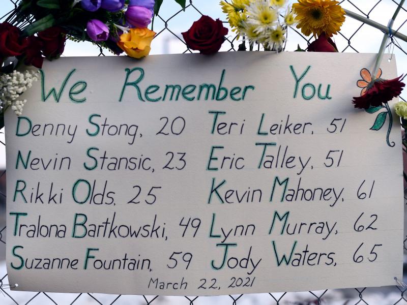 A sign framed with flowers lists victims' names on a fence outside a King Soopers grocery store in Boulder, Colo. The suspect in the mass shooting made his first court appearance on Thursday. A sign framed with flowers lists victims' names on a fence outside a King Soopers grocery store in Boulder, Colo. The suspect in the mass shooting made his first court appearance on Thursday.