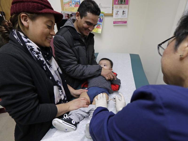 Matilde Gonzalez (left) and Cesar Calles hold their son, Cesar Julian Calles, 10 months old, as he is immunized with a flu shot in January at Sea Mar Community Health Center in Seattle. Matilde Gonzalez (left) and Cesar Calles hold their son, Cesar Julian Calles, 10 months old, as he is immunized with a flu shot in January at Sea Mar Community Health Center in Seattle.