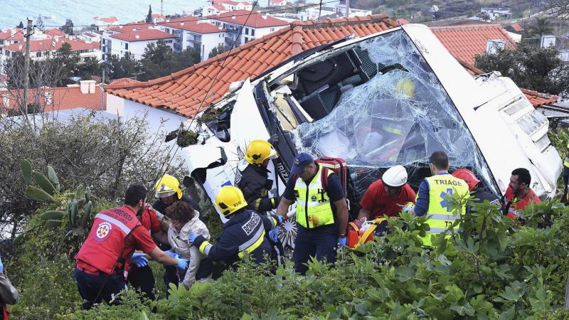 Rescue workers help a person who was inside a tour bus that crashed Wednesday in Caniço, a coastal town on Portugal's island of Madeira. Rescue workers help a person who was inside a tour bus that crashed Wednesday in Caniço, a coastal town on Portugal's island of Madeira.