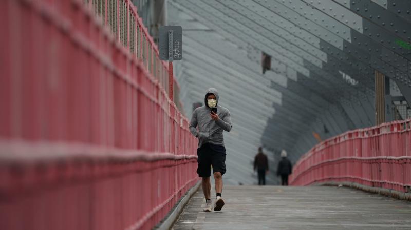 A pedestrian in a face mask crosses the Williamsburg Bridge in New York City last month. U.S. health authorities have announced they're changing the official recommendations on face masks, now urging people to wear them in public spaces to help slow the s A pedestrian in a face mask crosses the Williamsburg Bridge in New York City last month. U.S. health authorities have announced they're changing the official recommendations on face masks, now urging people to wear them in public spaces to help slow the s