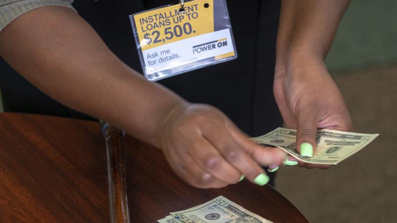 A manager of a financial services store in Ballwin, Mo., counts cash being paid to a client as part of a loan in 2018. Consumer groups blasted a new payday lending rule and its timing during a pandemic that has put tens of millions of people out of work. A manager of a financial services store in Ballwin, Mo., counts cash being paid to a client as part of a loan in 2018. Consumer groups blasted a new payday lending rule and its timing during a pandemic that has put tens of millions of people out of work.