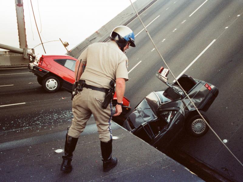 A California Highway Patrol officer checks cars that fell when the upper deck of the San Francisco Bay Bridge collapsed onto the lower deck after the 1989 Loma Prieta earthquake. A California Highway Patrol officer checks cars that fell when the upper deck of the San Francisco Bay Bridge collapsed onto the lower deck after the 1989 Loma Prieta earthquake.