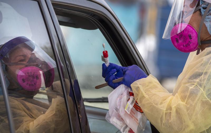 A member of the AltaMed Health Services staff prepares to take a sample at a drive-through coronavirus testing site in Los Angeles. A member of the AltaMed Health Services staff prepares to take a sample at a drive-through coronavirus testing site in Los Angeles.