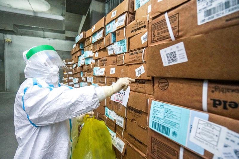 A health officer in a protective suit collects a sample from a package of imported frozen food for coronavirus rapid test at a wholesale market in China. A health officer in a protective suit collects a sample from a package of imported frozen food for coronavirus rapid test at a wholesale market in China.