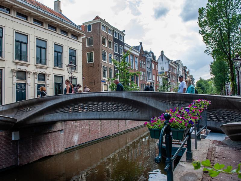 The almost 40-foot 3D-printed pedestrian bridge designed by Joris Laarman and built by Dutch robotics company MX3D has been opened in Amsterdam six years after the project was launched. The bridge, which was fabricated from stainless steel rods by six-axi The almost 40-foot 3D-printed pedestrian bridge designed by Joris Laarman and built by Dutch robotics company MX3D has been opened in Amsterdam six years after the project was launched. The bridge, which was fabricated from stainless steel rods by six-axi