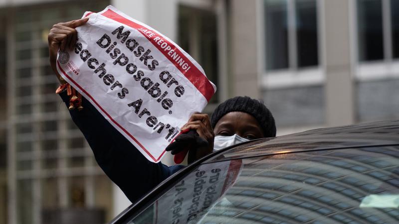 Chicago teachers have voted to accept an agreement for returning to in-person classes in the coming weeks. Here, a woman holds a sign at a car caravan in support of teachers' call for more safety precautions. Chicago teachers have voted to accept an agreement for returning to in-person classes in the coming weeks. Here, a woman holds a sign at a car caravan in support of teachers' call for more safety precautions.