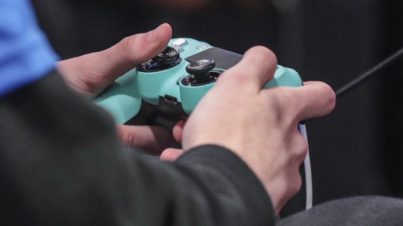 A person holding a PlayStation 4 controller. China is imposing curfews and regulations on video game playing minors. A person holding a PlayStation 4 controller. China is imposing curfews and regulations on video game playing minors.