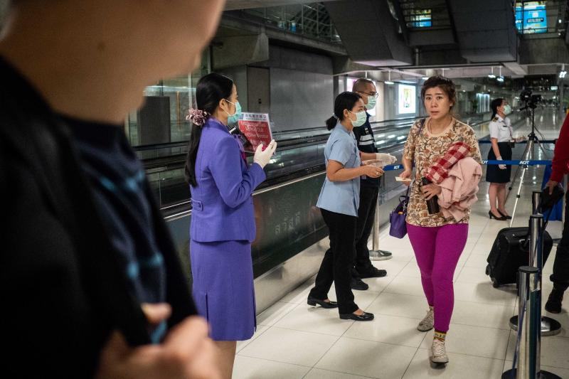 Public Health Officials hand out disease monitoring information after performing thermal scans on passengers arriving from Wuhan, China at Suvarnabumi Airport in Bangkok, Thailand. Public Health Officials hand out disease monitoring information after performing thermal scans on passengers arriving from Wuhan, China at Suvarnabumi Airport in Bangkok, Thailand.