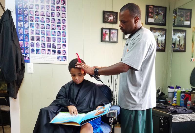 Jozef Jason, 7, reads a book to Ryan Griffin at the Fuller Cut in Ypsilanti, Mich., as part of the barbershop's literacy program. Jozef Jason, 7, reads a book to Ryan Griffin at the Fuller Cut in Ypsilanti, Mich., as part of the barbershop's literacy program.