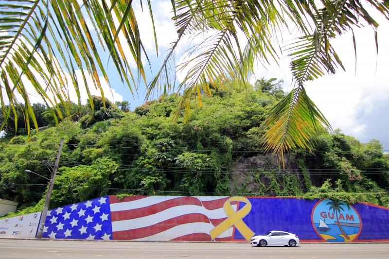 Afternoon traffic passes in front of a mural depicting the U.S. and Guam flags in the Tumon district on the island of Guam. Afternoon traffic passes in front of a mural depicting the U.S. and Guam flags in the Tumon district on the island of Guam.