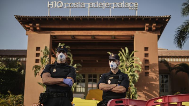 Police officers wear face masks Wednesday in front of a hotel on Tenerife, the largest of Spain's Canary Islands. Spanish officials say a hotel on the island has been placed under quarantine after an Italian doctor staying there tested positive for the ne Police officers wear face masks Wednesday in front of a hotel on Tenerife, the largest of Spain's Canary Islands. Spanish officials say a hotel on the island has been placed under quarantine after an Italian doctor staying there tested positive for the ne
