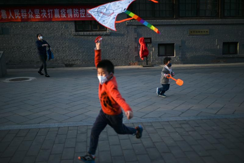 A boy wearing a face mask flies a kite at a park in Beijing. Researchers are studying the response of children to COVID-19. A boy wearing a face mask flies a kite at a park in Beijing. Researchers are studying the response of children to COVID-19.