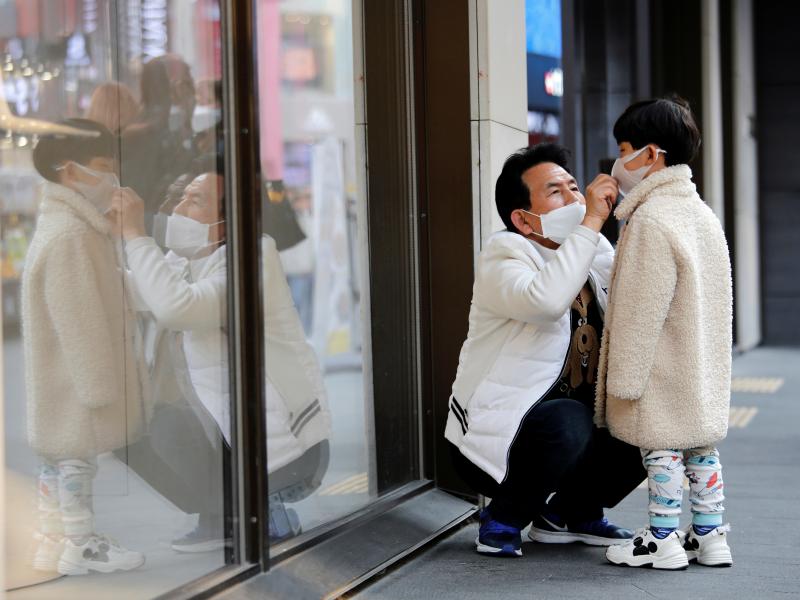 A man adjusts a boy's protective face mask on Thursday as they try to avoid contracting a new coronavirus in Seoul, South Korea. The country is reporting a spike in COVID-19 cases, predominantly in its south. A man adjusts a boy's protective face mask on Thursday as they try to avoid contracting a new coronavirus in Seoul, South Korea. The country is reporting a spike in COVID-19 cases, predominantly in its south.