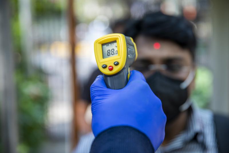 An office worker is screened with an infrared thermometer as he enters a building in New Delhi, India. An office worker is screened with an infrared thermometer as he enters a building in New Delhi, India.