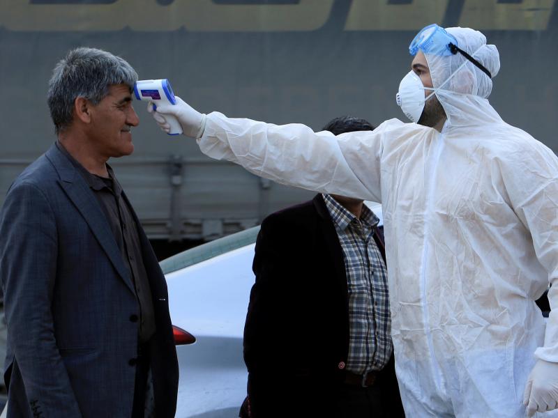 As the coronavirus that causes COVID-19 spreads to more areas, a health worker checks a man's temperature at a checkpoint on the outskirts of Duhok, Iraq, last Tuesday. As the coronavirus that causes COVID-19 spreads to more areas, a health worker checks a man's temperature at a checkpoint on the outskirts of Duhok, Iraq, last Tuesday.