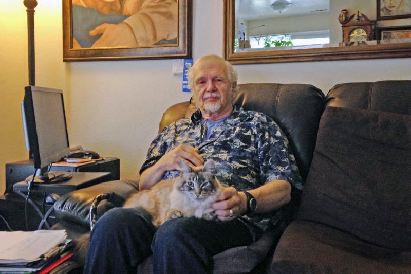 Retired California school teacher Mikkel Lawrence sits with his cat, Max. Lawrence has hepatitis C and has struggled to afford the medicine he needs to treat it. Retired California school teacher Mikkel Lawrence sits with his cat, Max. Lawrence has hepatitis C and has struggled to afford the medicine he needs to treat it.