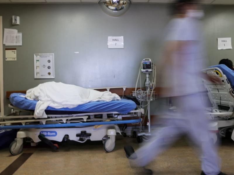 A patient lies on a stretcher in the hallway of the overloaded emergency room at Providence St. Mary Medical Center amid a surge in COVID-19 patients in Southern California in late December. Average new daily infections are now going down in California an A patient lies on a stretcher in the hallway of the overloaded emergency room at Providence St. Mary Medical Center amid a surge in COVID-19 patients in Southern California in late December. Average new daily infections are now going down in California an