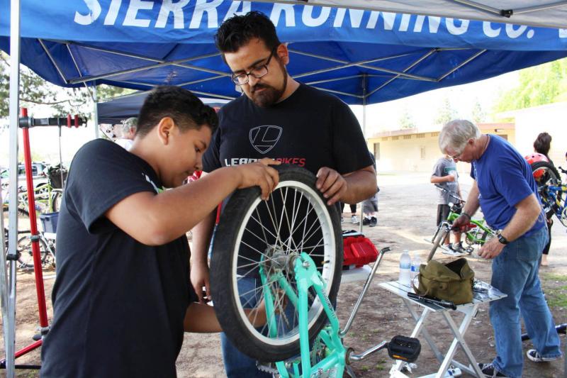 Jaime Rangel helps Gustavo Ruiz, 12, align a tire on his bike, at a recent community event in southeast Fresno, Calif. As manager for Bici Projects, Rangel promotes cycling in the Latino community as a great way to get in shape. Jaime Rangel helps Gustavo Ruiz, 12, align a tire on his bike, at a recent community event in southeast Fresno, Calif. As manager for Bici Projects, Rangel promotes cycling in the Latino community as a great way to get in shape.