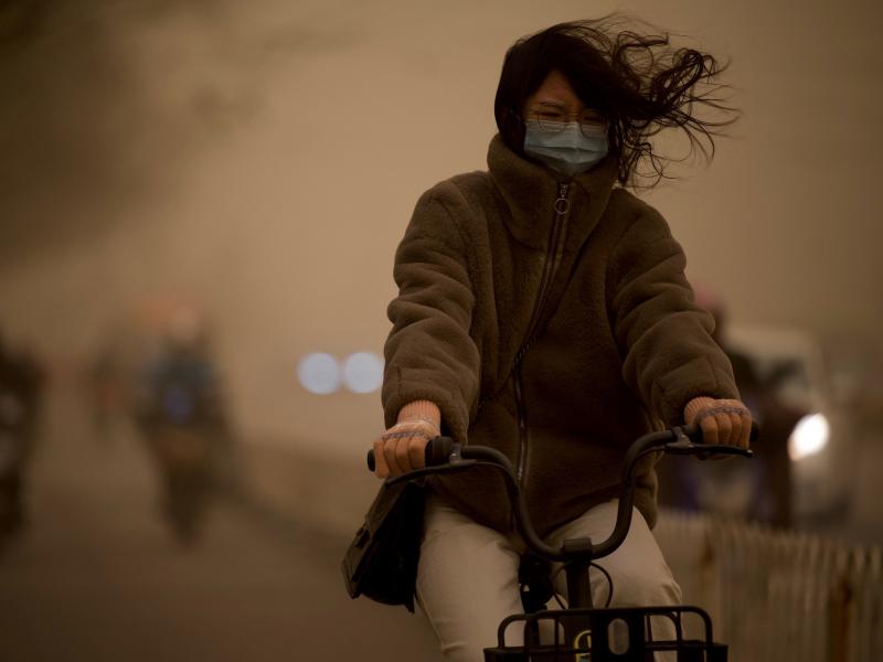 A woman cycles along a street during a sandstorm in Beijing on Monday. A woman cycles along a street during a sandstorm in Beijing on Monday.