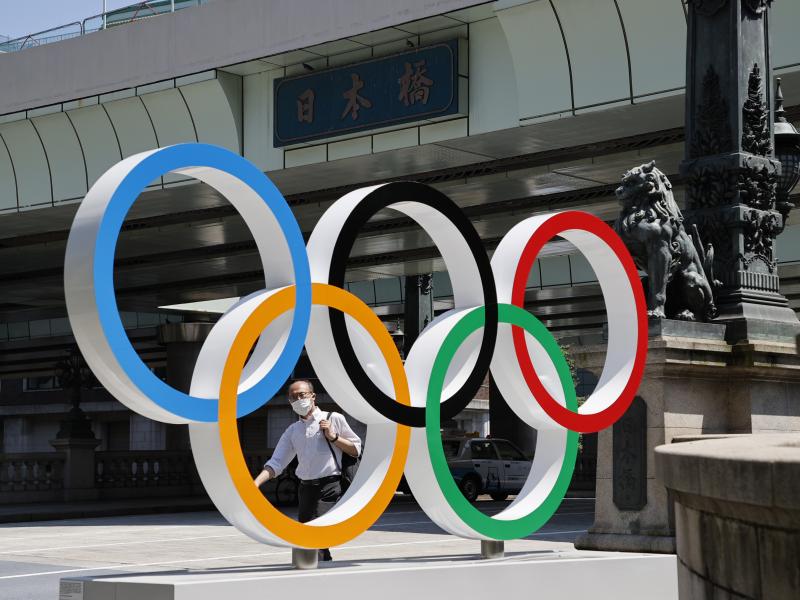 A man wearing a face mask walks past the Olympic Rings ahead of the Tokyo 2020 Olympic Games. The Games are scheduled to begin this week in Japan despite a global rise in coronavirus cases. A man wearing a face mask walks past the Olympic Rings ahead of the Tokyo 2020 Olympic Games. The Games are scheduled to begin this week in Japan despite a global rise in coronavirus cases.