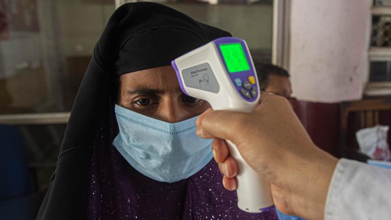 A health worker checks the temperature of passengers about to board a bus on Monday to their villages in Gauhati, India, after they were stranded during a lockdown to curb the spread of the new coronavirus. A health worker checks the temperature of passengers about to board a bus on Monday to their villages in Gauhati, India, after they were stranded during a lockdown to curb the spread of the new coronavirus.