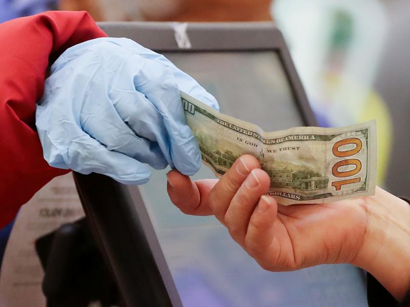 A woman wearing gloves pays for her purchase at a supermarket in Los Angeles. Bank regulators are urging consumers not to hoard cash, after reports of large withdrawals by some customers worried about the coronavirus. A woman wearing gloves pays for her purchase at a supermarket in Los Angeles. Bank regulators are urging consumers not to hoard cash, after reports of large withdrawals by some customers worried about the coronavirus.