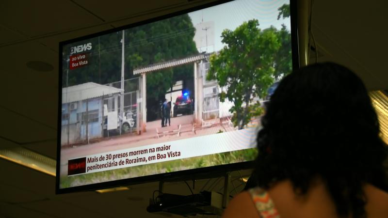 A woman watches a TV news report about the riot early Friday at a prison in Roraima, northern Brazil. A woman watches a TV news report about the riot early Friday at a prison in Roraima, northern Brazil.