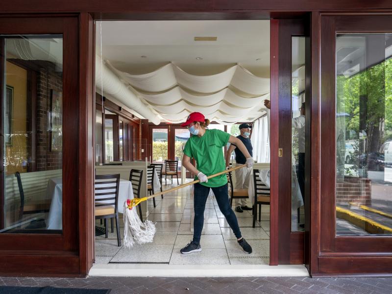 A cafe employee in Washington, D.C., cleans in preparation for reopening. A cafe employee in Washington, D.C., cleans in preparation for reopening.
