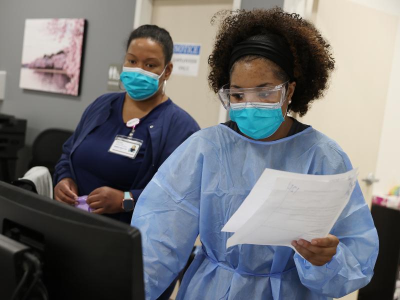 Workers at an urgent care facility in Woodbridge, Va., check health records while testing patients for COVID-19 on April 15, 2020. Workers at an urgent care facility in Woodbridge, Va., check health records while testing patients for COVID-19 on April 15, 2020.