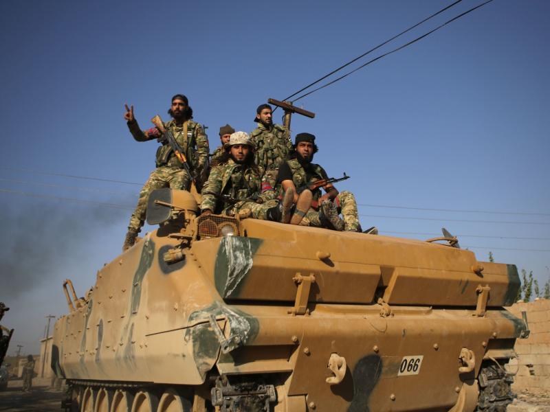 Turkey-backed Syrian fighters sit atop an armored personnel carrier in the southwestern neighborhoods of the border Syrian town of Tal Abyad on Sunday. The U.S. plans to evacuate its troops from northern Syria amid the Turkish offensive. Turkey-backed Syrian fighters sit atop an armored personnel carrier in the southwestern neighborhoods of the border Syrian town of Tal Abyad on Sunday. The U.S. plans to evacuate its troops from northern Syria amid the Turkish offensive.