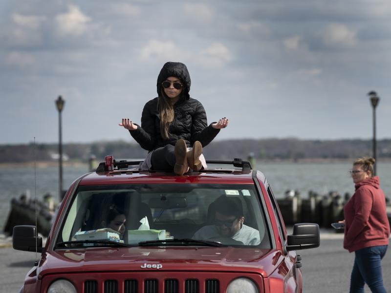 A member of Jesus' Church prays on top of a car during a Sunday church service held at Great Marsh Park in Cambridge, Maryland, on March 22, 2020. A member of Jesus' Church prays on top of a car during a Sunday church service held at Great Marsh Park in Cambridge, Maryland, on March 22, 2020.