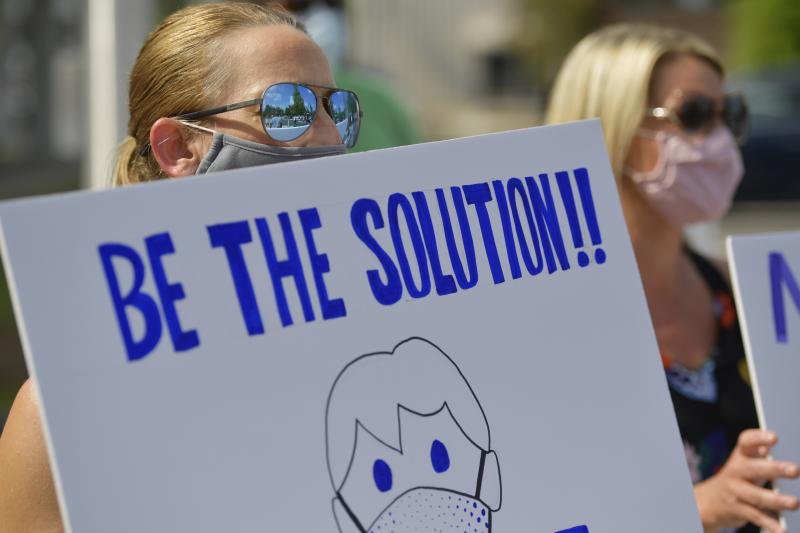 Demonstrators calling on people to wear masks gather outside school district headquarters in Marietta, Ga., last week. A recent review at pandemic data finds requiring masks, capping the size of gatherings and instituting certain bar, gym and restaurant r Demonstrators calling on people to wear masks gather outside school district headquarters in Marietta, Ga., last week. A recent review at pandemic data finds requiring masks, capping the size of gatherings and instituting certain bar, gym and restaurant r