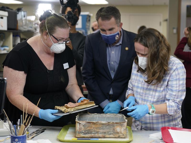 Virignia Gov. Ralph Northam ( center) watches as lead conservator for the Virginia Department of Historic Resources, Kate Ridgway (left) and Sue Donovon, conservator for Special Collections for the University of Virginia, remove the contents of a time cap Virignia Gov. Ralph Northam ( center) watches as lead conservator for the Virginia Department of Historic Resources, Kate Ridgway (left) and Sue Donovon, conservator for Special Collections for the University of Virginia, remove the contents of a time cap