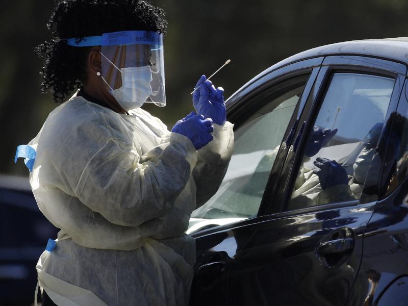 A health care worker with the UNLV School of Medicine tests a patient for the coronavirus at a drive-thru testing site in Las Vegas. A health care worker with the UNLV School of Medicine tests a patient for the coronavirus at a drive-thru testing site in Las Vegas.