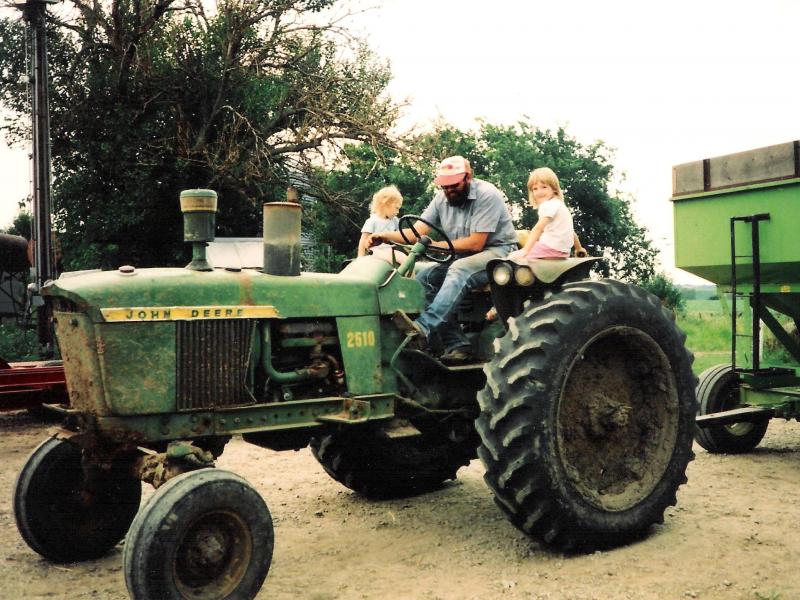 Karen (left) and Katie — still young girls at the time this photo was taken — sit with their father, Vern, on the family's tractor. Karen (left) and Katie — still young girls at the time this photo was taken — sit with their father, Vern, on the family's tractor.