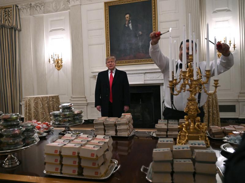 President Trump talks to the press about the table full of fast food laid out in the State Dining Room of the White House for a reception for the Clemson Tigers. President Trump talks to the press about the table full of fast food laid out in the State Dining Room of the White House for a reception for the Clemson Tigers.