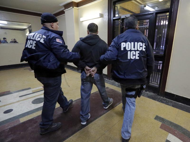 In this March 3, 2015, photo, Immigration and Customs Enforcement officers escort an arrestee in an apartment building in the Bronx borough of New York during a series of early morning raids. In this March 3, 2015, photo, Immigration and Customs Enforcement officers escort an arrestee in an apartment building in the Bronx borough of New York during a series of early morning raids.