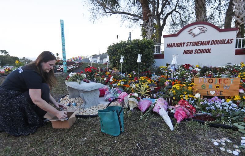Suzanne Devine Clark, an art teacher at Deerfield Beach Elementary School, places painted stones at a memorial outside Marjory Stoneman Douglas High School during the one-year anniversary of the school shooting on Feb. 14, 2019, in Parkland, Fla. The stat Suzanne Devine Clark, an art teacher at Deerfield Beach Elementary School, places painted stones at a memorial outside Marjory Stoneman Douglas High School during the one-year anniversary of the school shooting on Feb. 14, 2019, in Parkland, Fla. The stat