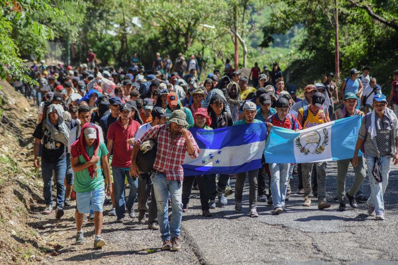Migrants heading toward the U.S. carry Honduran and Guatemalan national flags in Guatemala on Monday. President Trump has threatened to cut off aid to Honduras, Guatemala and El Salvador for failing to stop the caravan's journey. Migrants heading toward the U.S. carry Honduran and Guatemalan national flags in Guatemala on Monday. President Trump has threatened to cut off aid to Honduras, Guatemala and El Salvador for failing to stop the caravan's journey.